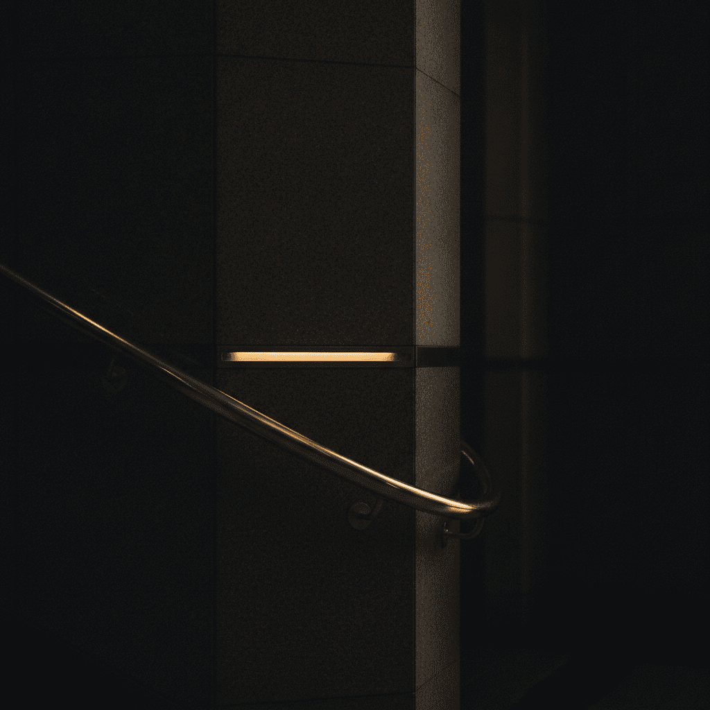 Brass institutional handrail catching warm light against dark stone in a civic building